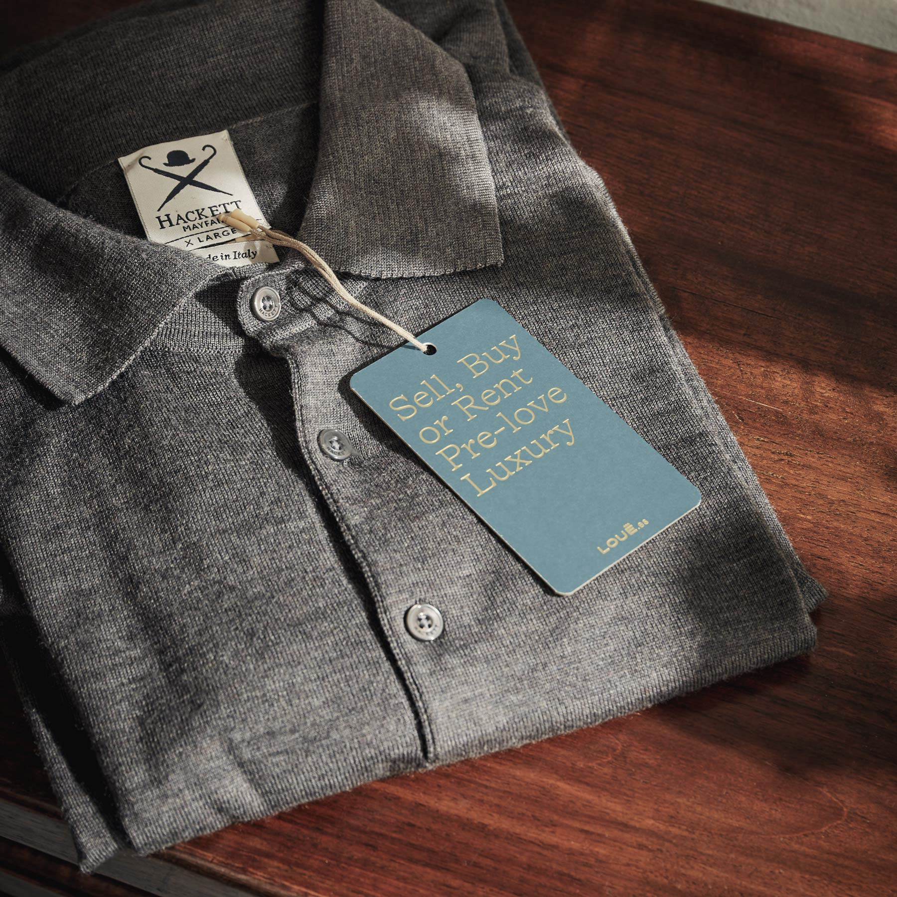 Detalle del reverso de la etiqueta de la tienda de moda de lujo Louë de Madrid con eslogan corporativo colgando de un polo